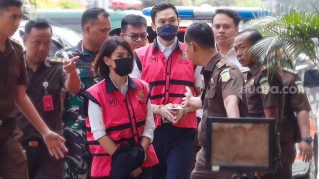 Tersangka kasus dugaan korupsi di PT Timah Harvey Moeis (kedua kanan) bersama Helena Lim (kedua kiri) berjalan memasuki gedung saat pelimpahan tahap dua di Kejaksaan Negeri Jakarta Selatan, Jakarta, Senin (22/7/2024). [Suara.com/Alfian Winanto]