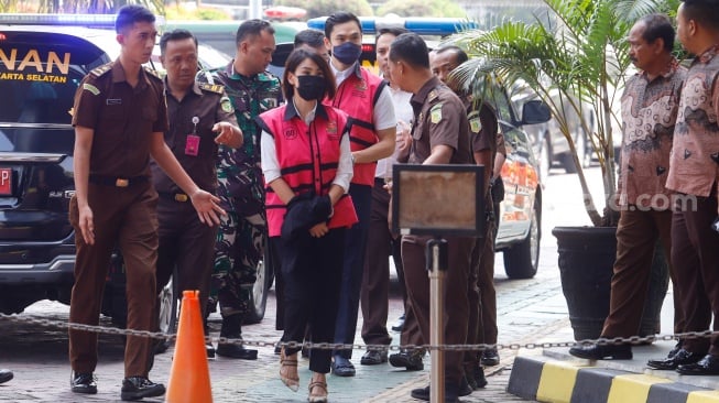 Tersangka kasus dugaan korupsi di PT Timah Harvey Moeis (tengah,belakang) bersama Helena Lim (tengah) berjalan memasuki gedung saat pelimpahan tahap dua di Kejaksaan Negeri Jakarta Selatan, Jakarta, Senin (22/7/2024). [Suara.com/Alfian Winanto]