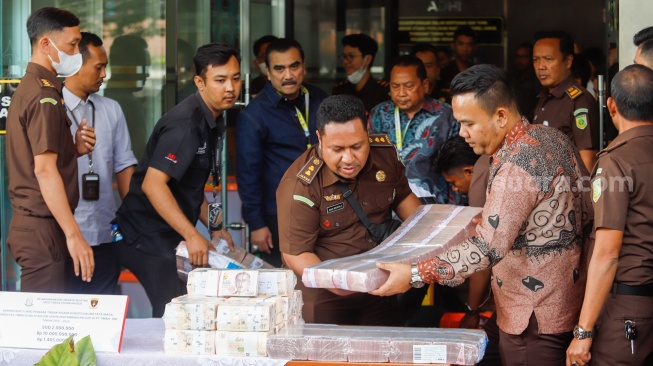 Petugas Kejaksaan menampilkan barang bukti berupa uang tunai dan tas mewah milik tersangka kasus dugaan korupsi di PT Timah Harvey Moeis dan Helena Lim di Kejaksaan Negeri Jakarta Selatan, Senin (22/7/2024). [Suara.com/Alfian Winanto]