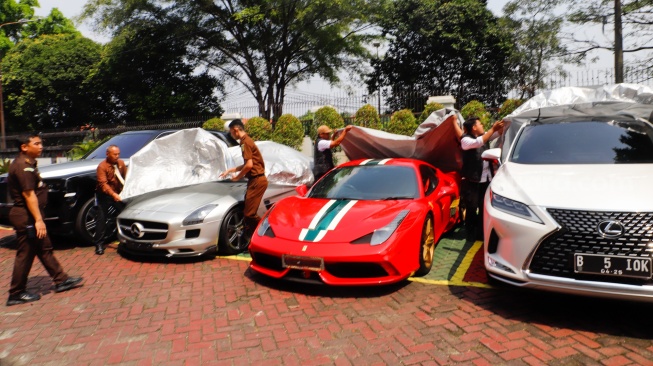 Petugas Kejaksaan menampilkan barang bukti berupa uang tunai dan tas mewah milik tersangka kasus dugaan korupsi di PT Timah Harvey Moeis dan Helena Lim di Kejaksaan Negeri Jakarta Selatan, Senin (22/7/2024). [Suara.com/Alfian Winanto]