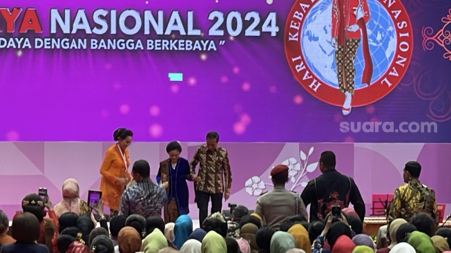 Momen Presiden Jokowi menggandeng tangan Ibu Negara Iriana membuat emak-emak berkebaya di Istora Senayan riuh. (Suara.com/Novian)