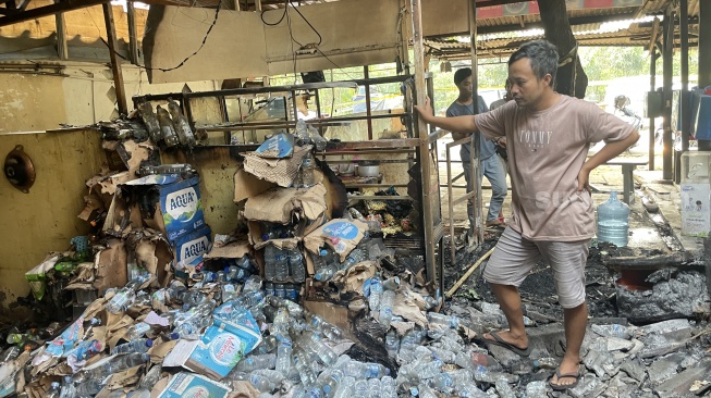 Pemilik warung di dekat pos polisi Bintaro, Iis alias bewok meninjau warung miliknya yang ikut terbakar saat insiden kebakaran. [Wivy Hikmatullah]