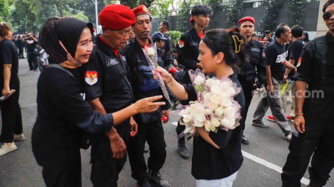 Massa dari unsur badan dan sayap pusat Partai Demokrasi Indonesia Perjuangan (PDIP) membagikan bunga saat menggelar aksi di depan gedung Komnas HAM di Jakarta, Jumat (27/7/2024). [Suara.com/Alfian Winanto]