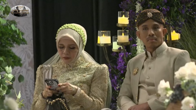 Potret Geni Faruk sedang sibuk bermain handphone sebelum akad nikah Thariq Halilintar dan Aaliyah Massaid pada Jumat (26/7/2024) (YouTube/Thariq Halilintar)