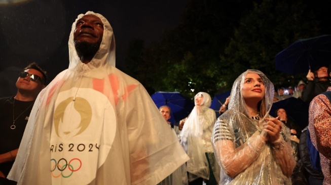 Penonton mengenakan ponco untuk berteduh dari hujan menyaksikan upacara pembukaan Olimpiade Paris 2024 pada 26 Juli 2024 di Paris, Prancis. Steph Chambers / POOL / AFP