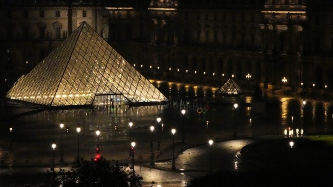 Pembawa obor terlihat di Museum Louvre selama upacara pembukaan Olimpiade Paris 2024 di Paris pada 26 Juli 2024.Xia Yifang / POOL / AFP