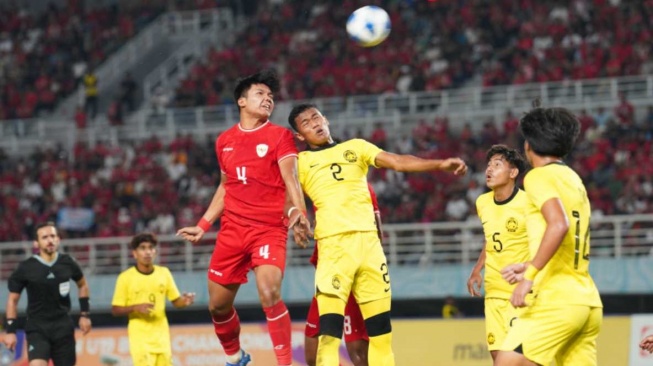 Bek Timnas Indonesia U-19, Kadek Arel saat berduel udara dengan pemain Malaysia U-19 dalam laga semifinal Piala AFF U-19 2024 di Stadion Gelora Bung Tomo (GBT), Surabaya, Jawa Timur, Sabtu (27/7/2024) malam WIB. [Dok. PSSI]