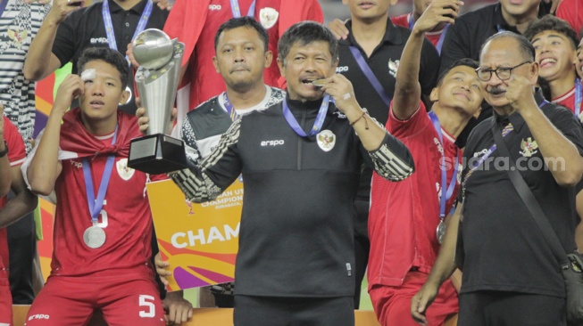 Pelatih Timnas Indonesia U-19, Indra Sjafri mengangkat trofi juara Piala AFF U-19 2024. Timnas Garuda Nusantara juara usai mengalahkan Thailand, 1-0 dalam laga final di Stadion Gelora Bung Tomo (GBT), Surabaya, Senin (29/7/2024). [Suara.com/Ronald Seger Prabowo]