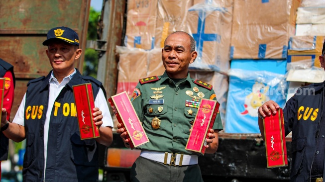 Petugas melakukan pemusnahan minuman keras ilegal hasil penindakan di Kantor Pusat Bea Cukai, Jakarta, Rabu (31/7/2024). [Suara.com/Alfian Winanto]