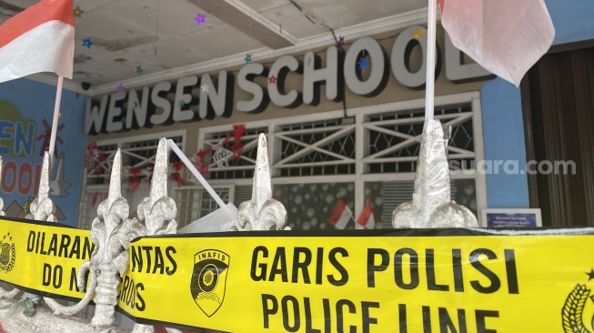 Polisi memasang garis polisi atau police line di tempat penitipan anak alias daycare Wensen School, Jalan Putri Tunggal nomor 42, Harjamukti, Cimanggis, Depok, Jawa Barat. (Suara.com/Faqih)