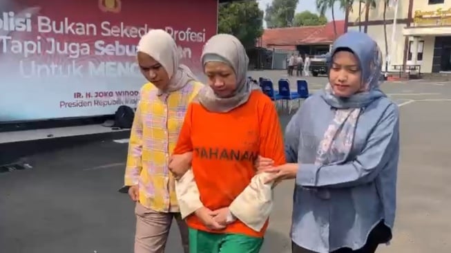 Meita Irianty, tersangka penganiayaan terhadap balita berumur dua tahun di Daycare miliknya  tertunduk saat digelandang polisi di Markas Polres Metro Depok, Kamis (1/8/2024). [Suara.com/Faqih]