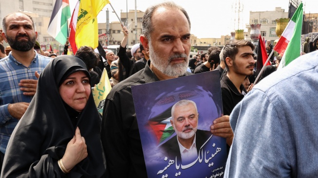 Warga Iran memegang potret mendiang pemimpin Hamas Ismail Haniyeh selama prosesi pemakamannya di Teheran, Iran, Kamis (1/8/2024). [AFP]