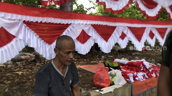 Suraji menceritakan, dirinya telah jualan bendera merah putih sejak tahun 2019. Saat itu, omzet yang ia dapat per hari bisa mencapai Rp1,5 juta. [Suara.com/Mae Harsa]