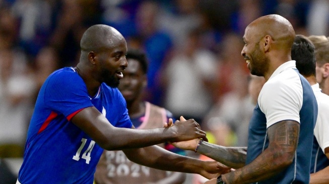 Penyerang Prancis, Jean-Philippe Mateta merayakan gol kedua timnya bersama pelatih Thierry Henry selama pertandingan semifinal sepak bola putra Olimpiade 2024 antara Prancis vs Mesir di Stadion Lyon di Lyon pada 5 Agustus 2024.Olivier CHASSIGNOLE / AFP