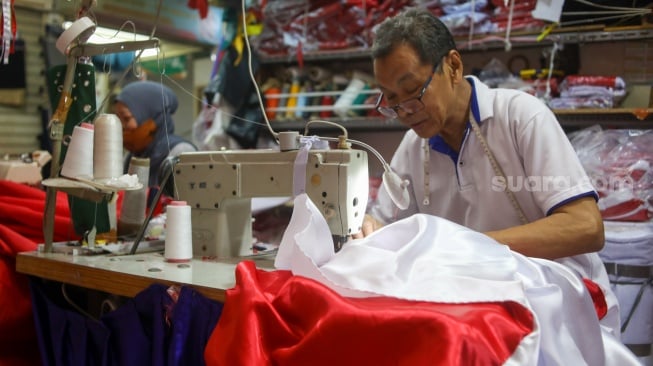 Penjahit menyelesaikan pesanan rempel bendera di Pasar Senen, Jakarta, Rabu (7/8/2024). [Suara.com/Alfian Winanto]