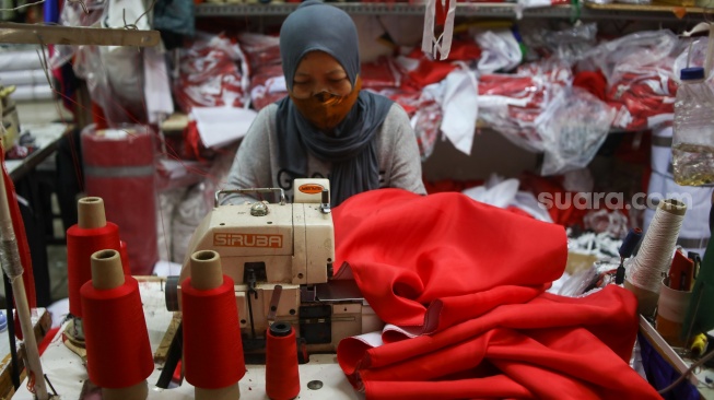 Penjahit menyelesaikan pesanan rempel bendera di Pasar Senen, Jakarta, Rabu (7/8/2024). [Suara.com/Alfian Winanto]