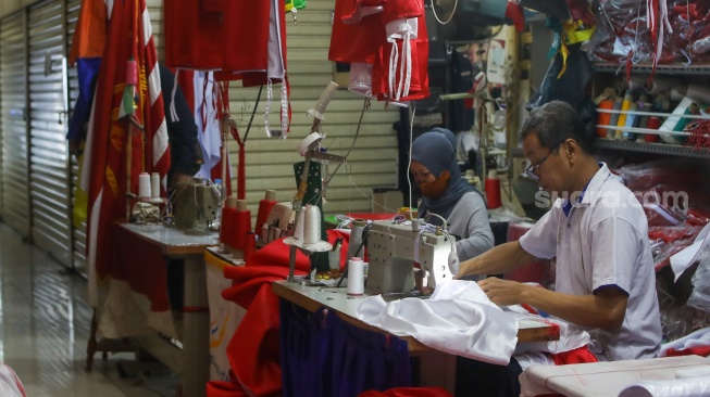 Penjahit menyelesaikan pesanan rempel bendera di Pasar Senen, Jakarta, Rabu (7/8/2024). [Suara.com/Alfian Winanto]