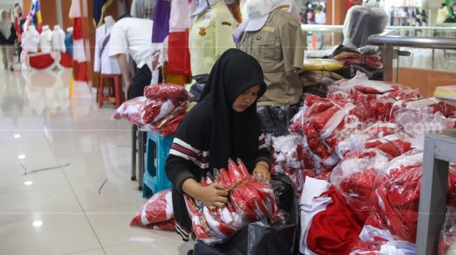 Penjahit menyelesaikan pesanan rempel bendera di Pasar Senen, Jakarta, Rabu (7/8/2024). [Suara.com/Alfian Winanto]