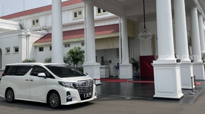 Toyota Alphard warna putih berpelat B 88 PSD terparkir di dekat pilar Istana Kepresidenan Jakarta. (Suara.com/Novian)