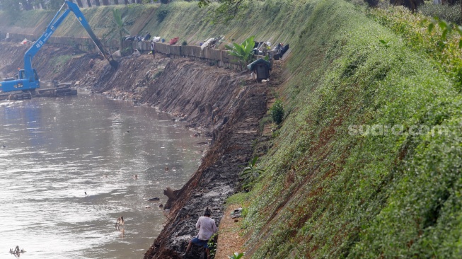 Pekerja menggunakan alat berat mengeruk lumpur endapan Kali Ciliwung di kawasan Manggarai, Jakarta, Kamis (8/8/2024). [Suara.com/Alfian Winanto]