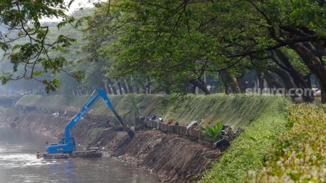 Pekerja menggunakan alat berat mengeruk lumpur endapan Kali Ciliwung di kawasan Manggarai, Jakarta, Kamis (8/8/2024). [Suara.com/Alfian Winanto]