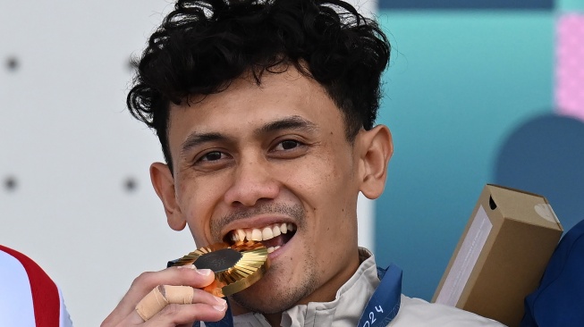 Atlet panjat tebing putra Indonesia Veddriq Leonardo menggigit medali emas usai menjuarai nomor speed putra Olimpiade Paris 2024 di Le Bourget Climbing Venue, Paris, Prancis, Kamis (8/8/2024). [ANTARA FOTO/Wahyu Putro A/sgd/rwa]