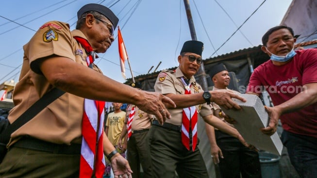 Ketua Kwarnas Gerakan Pramuka Budi Waseso (tengah) membantu memasukkan bahan bangunan untuk bedah rumah warga saat kegiatan bakti sosial pramuka di Kebon Bawang, Jakarta Utara, Jumat (9/8/2024). [Suara.com/Alfian Winanto]