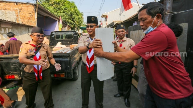 Ketua Kwarnas Gerakan Pramuka Budi Waseso (tengah) membantu memasukkan bahan bangunan untuk bedah rumah warga saat kegiatan bakti sosial pramuka di Kebon Bawang, Jakarta Utara, Jumat (9/8/2024). [Suara.com/Alfian Winanto]