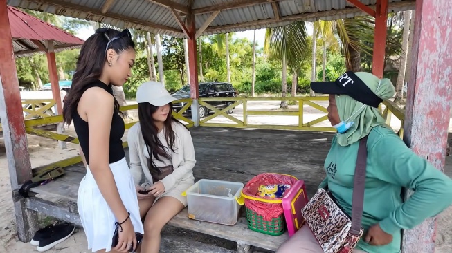 Potret Fujianti Utami Putri alias Fuji sedang memborong dagangan ibu-ibu keliling di Pantai Toronipa (YouTube/Fuji An)