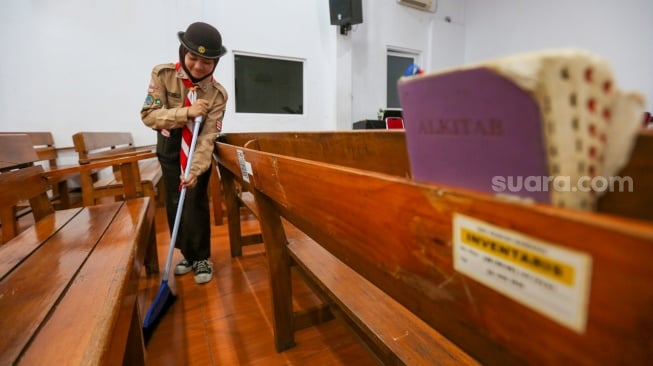 Anggota Pramuka membersihkan ruangan ibadah saat kegiatan bakti sosial pramuka di Gereja Kristen Indonesia, Kebon Bawang, Jakarta Utara, Jumat (9/8/2024). [Suara.com/Alfian Winanto]