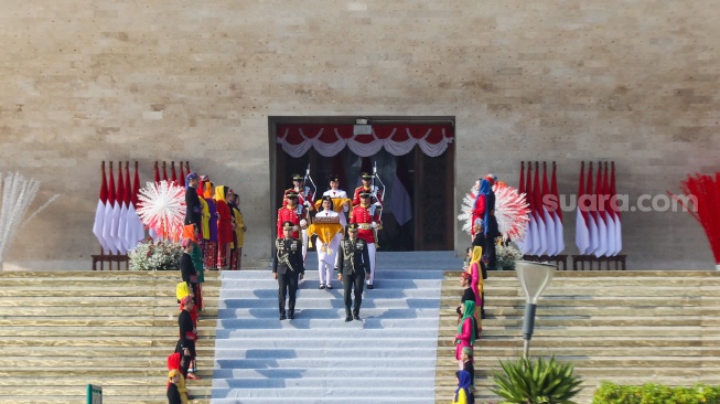 Tim Purna Paskibraka 2023 membawa duplikat bendera Merah Putih berjalan menuju kendaraan taktis maung dalam acara kirab bendera Merah Putih dan naskah teks proklamasi menuju Ibu Kota Nusantara (IKN) di kawasan Monumen Nasional (Monas), Jakarta, Sabtu (10/8/2024). [Suara.com/Alfian Winanto]