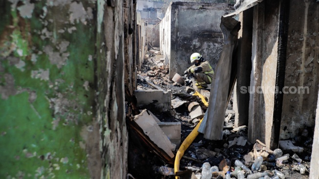 Petugas pemadam beristirahat saat melakukan pendinginan pada sisa-sisa rumah yang terbakar di kawasan Manggarai, Selasa (13/8/2024). [Suara.com/Alfian Winanto]