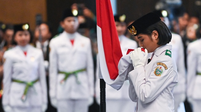 Anggota Paskibraka 2024 asal Sumatera Utara Violetha Agryka Sianturi mencium Bendera Merah-Putih dalam pengukuhan Paskibraka Tingkat Pusat 2024 di Istana Negara, Ibu Kota Nusantara (IKN), Kalimantan Timur, Selasa (13/8/2024). [ANTARA FOTO/Sigid Kurniawan].