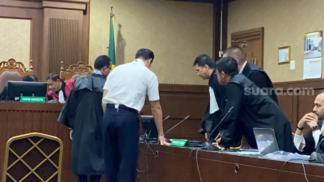 Harvey Moeis, suami Sandra Dewi saat berdiskusi dengan kuasa hukum saat menjalani sidang perdana kasus korupsi timah di Pengadilan Tindak Pidana Korupsi (Tipikor) Jakarta, Rabu (14/8/2024). [Suara.com/Tiara Rosana]