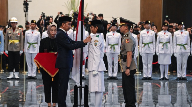 Presiden Joko Widodo (kedua kiri) selaku pembina upacara menyematkan lencana kepada anggota Paskibraka 2024 asal Sumatera Utara Violetha Agryka Sianturi (kedua kanan) dalam pengukuhan Paskibraka Tingkat Pusat 2024 di Istana Negara, Ibu Kota Nusantara (IKN), Kalimantan Timur, Selasa (13/8/2024). [ANTARA FOTO/Sigid Kurniawan]