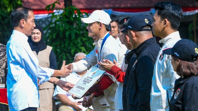 Presiden Joko Widodo (kiri) memberikan bonus kepada Lifter putra peraih medali emas Olimpiade Paris 2024 Rizki Juniansyah (kedua kiri) di halaman Istana Merdeka, Jakarta, Kamis (15/8/2024). [ANTARA FOTO/Muhammad Adimaja/Spt]