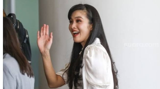 Artis Sandra Dewi menyapa wartawan saat datang untuk menjalani pemeriksaan di Gedung Kejaksaan Agung RI, Jakarta, Kamis (4/4/2024). [Suara.com/Alfian Winanto]