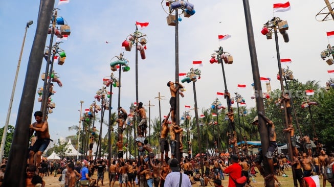 Peserta mengikuti lomba panjat pinang di Pantai Festival, Taman Impian Jaya Ancol, Jakarta, Sabtu (17/8/2024). [Suara.com/Alfian Winanto]