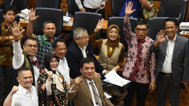 Menteri Hukum dan HAM Supratman Andi Agtas (kanan) dan Menteri Dalam Negeri Tito Karnavian (keempat kanan), bersama Wakil Ketua Badan Legislasi DPR yang juga pimpinan rapat Achmad Baidowi (kedua kanan), dan perwakilan fraksi yang menyetujui RUU melambaikan tangan usai menandatangani naksah persetujuan RUU Pilkada dalam rapat pengambilan keputusan pembahasan RUU Pilkada antara Baleg DPR dengan Pemerintah di Kompleks Parlemen, Senayan, Jakarta, Rabu (21/8/2024). Badan Legislasi DPR mengesahkan Revisi Undang-Undang (RUU) Pilkada dibawa ke rapat Paripurna untuk disahkan menjadi UU, dimana sebanyak delapan Fraksi DPR menyetujui RUU Pilkada dan hanya Fraksi PDI Perjuangan yang tak sependapat RUU tersebut dibawa ke Rapat Paripurna. ANTARA FOTO/Indrianto Eko Suwarso/rwa.