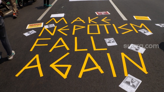 Massa aksi yang terdiri dari sejumlah elemen buruh, mahasiswa dan elemen masyarakat mebuat tulisan di jalan saat menggelar aksi unjuk rasa di depan gedung DPR, Jakarta, Kamis (22/8/2024). [Suara.com/Alfian Winanto]
