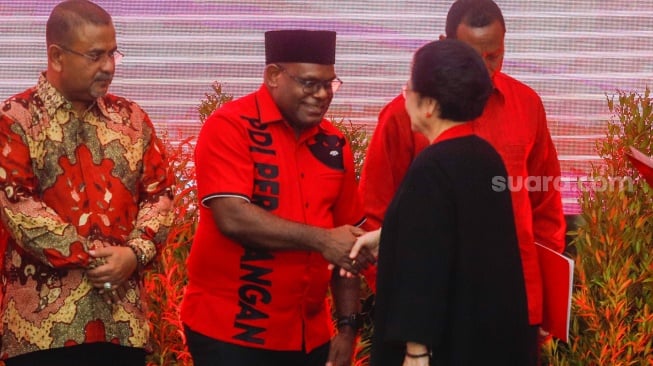 Ketua Umum PDI Perjuangan Megawati Soekarnoputri (kanan) menyerahkan surat rekomendasi partai kepada Bakal Calon Gubernur Papua Tengah Meki Fritz Nawipa (tengah) saat acara pengumuman para Calon Kepala Daerah di Kantor DPP PDIP, Jakarta, Kamis (22/8/2024). [Suara.com/Alfian Winanto]
