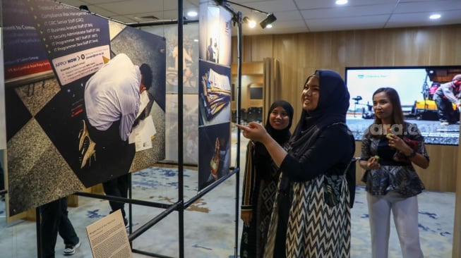 Pengunjung melihat karya foto yang dipamerkan pada pameran foto Rekam Jakarta di Perpustakaan Jakarta Galeri PDS HB Jassin, Taman Ismail Marzuki (TIM), Jakarta, Sabtu (24/08/2024). [Suara.com/Alfian Winanto]