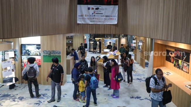 Pengunjung melihat karya foto yang dipamerkan pada pameran foto Rekam Jakarta di Perpustakaan Jakarta Galeri PDS HB Jassin, Taman Ismail Marzuki (TIM), Jakarta, Sabtu (24/08/2024). [Suara.com/Alfian Winanto]