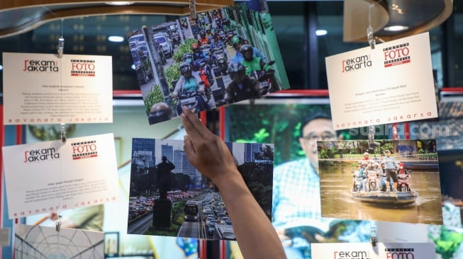 Pengunjung melihat karya foto yang dipamerkan pada pameran foto Rekam Jakarta di Perpustakaan Jakarta Galeri PDS HB Jassin, Taman Ismail Marzuki (TIM), Jakarta, Sabtu (24/08/2024). [Suara.com/Alfian Winanto]