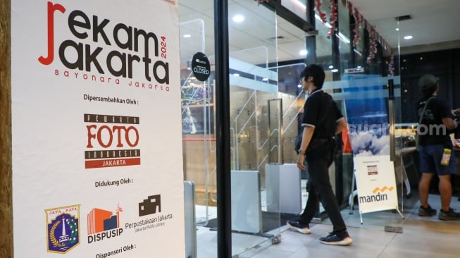 Pengunjung melihat karya foto yang dipamerkan pada pameran foto Rekam Jakarta di Perpustakaan Jakarta Galeri PDS HB Jassin, Taman Ismail Marzuki (TIM), Jakarta, Sabtu (24/08/2024). [Suara.com/Alfian Winanto]