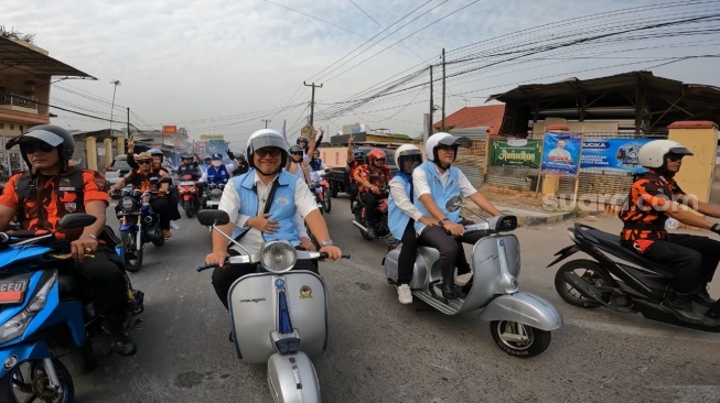 Paslon Helldy Agustian dan Alawi Mahmud mengendarai vespa ke Kantor KPU Kota Cilegon, Rabu (29/8/2024). [Istimewa]