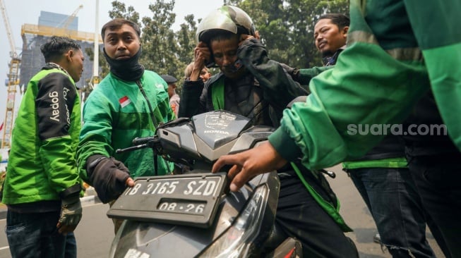 Massa pengemudi ojek online atau ojek daring melakukan aksi sweeping saat akan berunjuk rasa di kawasan Patung Kuda, Jakarta, Kamis (29/8/2024). [Suara.com/Alfian Winanto]