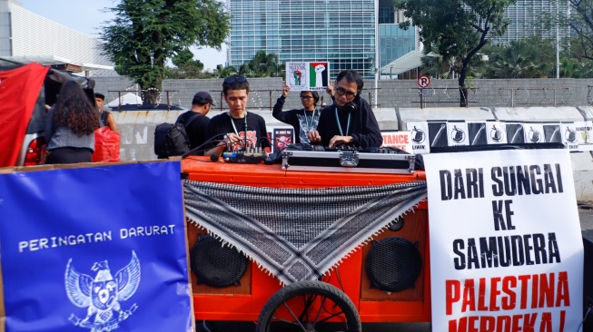 Peserta aksi mengangkat poster berisi kritikan saat menggelar aksi bela Palestina di depan Kedutaan Besar Amerika, Jakarta, Jumat (30/8/2024). [Suara.com/Alfian Winanto]