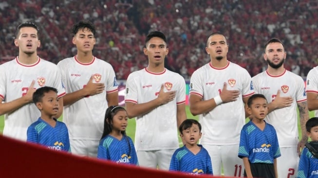 Para pemain Timnas Indonesia menyanyikan lagu kebangsaan bersama maskot sebelum pertandingan kualifikasi Piala Dunia 2026 melawan Australia di Stadion Gelora Bung Karno, Jakarta, pada 10 September 2024.BAY ISMOYO / AFP.