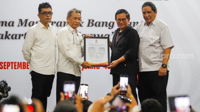 Relawan memberikan Plakat kepada Bakal Calon Gubernur Jakarta Pramono Anung saat Deklarasi Rumah Bersama Pramono-Rano di Gedung Joeang 45, Jakarta, Rabu (11/9/2024). [Suara.com/Alfian Winanto]